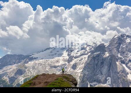 Ciclista con una mountain bike elettrica (e-bike) lungo il sentiero Viel del Pan (Bindelweg) di fronte alla Marmolada, Padon cresta ai confini Foto Stock