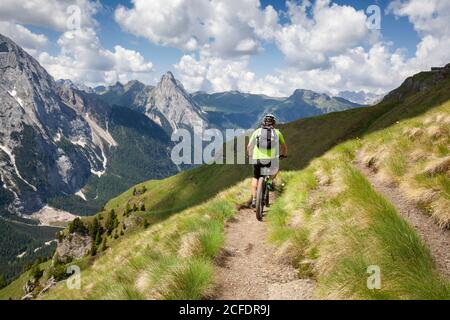 Ciclista con una mountain bike elettrica (e-bike) lungo il sentiero Viel del Pan (Bindelweg) di fronte alla Marmolada, Padon cresta ai confini Foto Stock