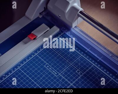 Da sopra la macchina manuale di taglio della carta con il grafico blu con il formato linee su tavolo di legno Foto Stock