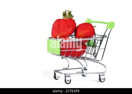 Carrello supermercato con fragole su sfondo bianco. Vendita di bacche. Foto Stock