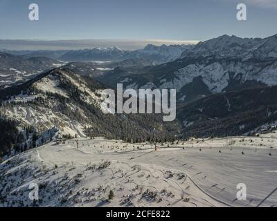 Vista aerea della pista sciistica di Längenfeld (comprensorio sciistico Garmisch Classic) con vista verso i Monti Karwendel in inverno, cielo blu, nuvole, Foto Stock