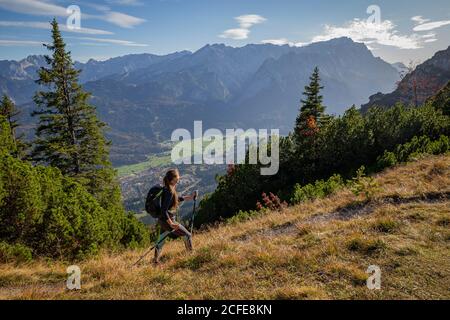 Giovane donna che si avvicina a Kramer in autunno con vista su Garmisch-Partenkirchen e sui Monti Wetterstein con Alpspitze, Zugspitze, e. Foto Stock