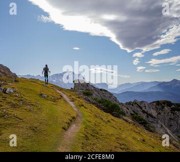 La giovane donna che si avvicina a Kramer guarda verso i Monti Wetterstein (con Zugspitze) e a destra le Alpi Ammergau, cielo blu, nuvole, Foto Stock