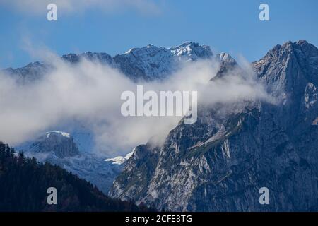 Nuvole di nebbia avvolge Waxensteine e Höllental così come Zugspitze, Wetterstein Montagne, cielo blu, nebbia, nuvole, Garmisch-Partenkirchen, Upper Foto Stock