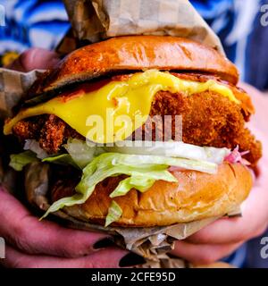 Persona con unghie verniciate nere che tiene UN Vegano fresco Burger a base di piante in un bun Foto Stock