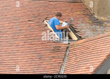 Un costruttore che monta una finestra lucernario nel tetto di una proprietà a Westcliff on Sea, Essex, Regno Unito, durante la lettura delle istruzioni. Uomo d'artigianato bianco Foto Stock