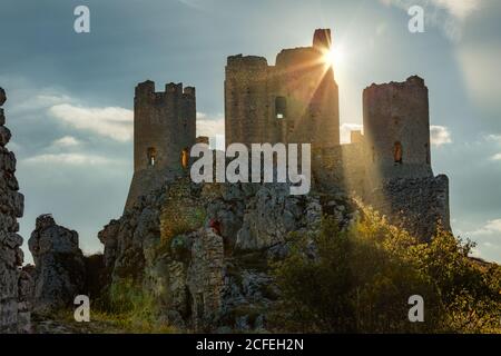 I raggi del sole tramontato dietro il castello di Rocca Calascio nel Parco Nazionale del Gran Sasso e dei Monti della Laga. Rocca Calascio, Abruzzo Foto Stock
