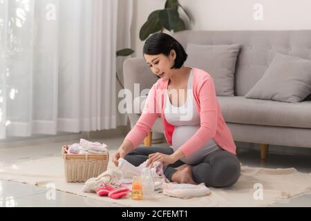 Allegro incinta preparare i vestiti del bambino e fare per fare la lista, ottenendo pronto per la consegna del bambino Foto Stock