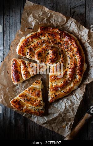 Dall'alto cuocete tenendo la teglia calda con il fresco sfoglia la pasta e servi un pezzo di borek sul piatto Foto Stock