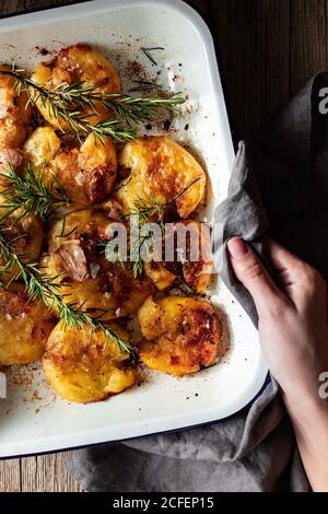 Da sopra raccolto anonimo persona mani che tengono piatto bianco caldo con il tovagliolo delizioso gamberi fritti servito con rosmarino fresco e fiocchi di sale Foto Stock