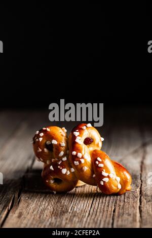 Deliziosi focaccine di zafferano tradizionali appena sfornate con uva passa tavolo di legno su sfondo nero Foto Stock