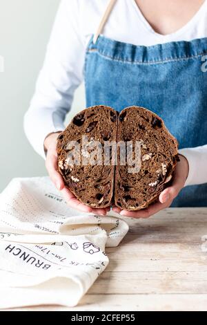 Mani di Donna in grembiule che tengono pane di segale con uvetta e noci Foto Stock