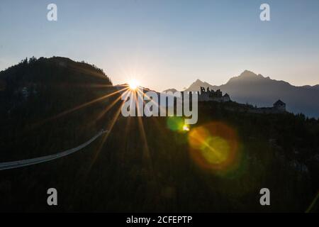 Il sole del mattino brillante splende sul cielo senza nuvole sopra la dorsale di montagna E vecchio castello in Austria Foto Stock