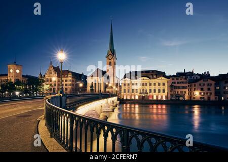 Paesaggio urbano illuminato di Zurigo con la chiesa di Fraumunster al crepuscolo, Svizzera Foto Stock