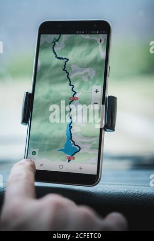 Closeup mano di turista anonimo utilizzando navigatore GPS su moderno smartphone in auto durante il viaggio Foto Stock