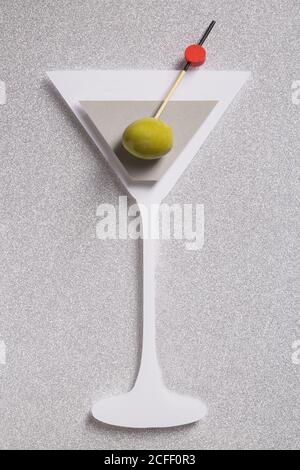 Silhouette di un cocktail martini fatto con cartone con vero oliva su sfondo argento scintillato Foto Stock