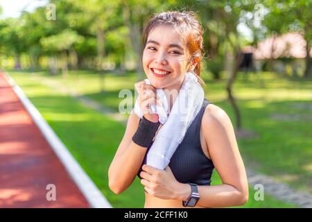 Happuy bella giovane donna asiatica che si esercita su una pista di corsa asciugando il sudore con il suo asciugamano bianco dopo di lei corsa mattutina Foto Stock