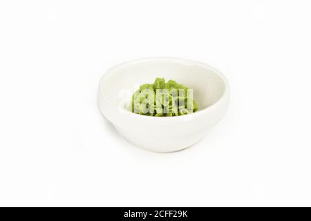 Ciotola con salsa wasabi su un piatto bianco. Per il menu del ristorante. Piatto di condimento tradizionale cinese classico wasabi. Cucina giapponese, pasta di rafano. Foto Stock