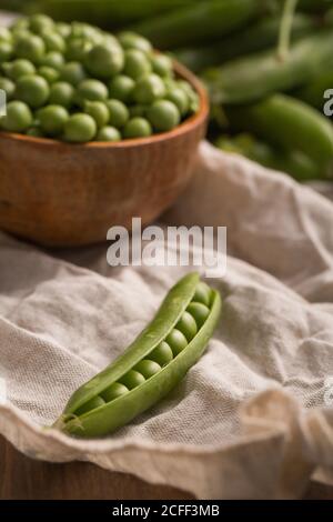 Piselli freschi in una paletta di legno posta in un trasparente stoffa su un tavolo di legno Foto Stock