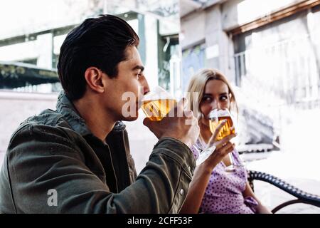 Giovane coppia allegra e attraente, gustando un drink rinfrescante durante la passeggiata città in caldo giorno Foto Stock
