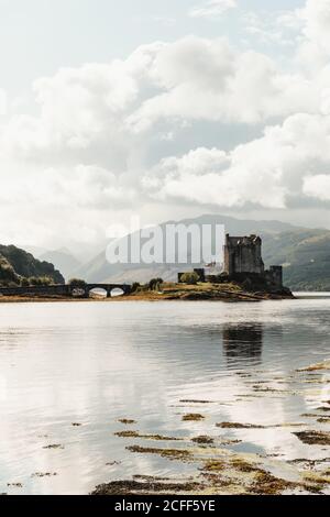 Meraviglioso scenario di abbandonato castello medievale circondato dal fiume contro valle foggy sotto il cielo blu con le nuvole bianche lussureggianti dentro Scozia Foto Stock