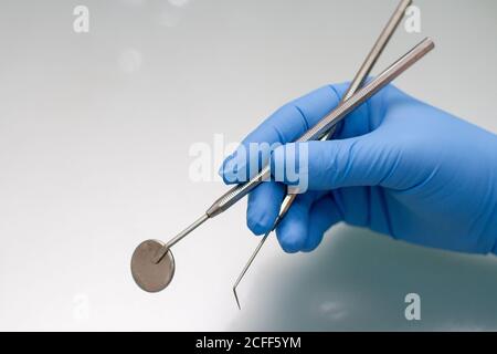 Le mani del medico dentista in guanti blu medico con attrezzi dentali Foto Stock