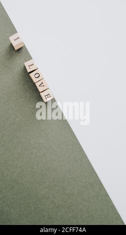 Dall'alto iscrizione minimalista amo fatta da lettere di legno disposte in diagonale su superfici verdi e bianche Foto Stock