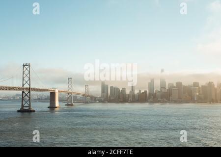 Ponte di metallo che si estende verso il centro in nuvoloso foschia sopra l'acqua A San Francisco Foto Stock