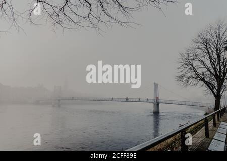 Persone che camminano attraverso il fiume sul ponte moderno con nebbia giorno nuvoloso Foto Stock