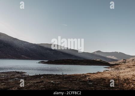 Paesaggio panoramico di montagna con rocce e lago contro chiaro cielo blu all'alba Foto Stock