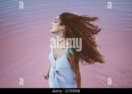 Giovane bella Donna con capelli ricci lunghi vestito estivo godendo brezza marina Foto Stock