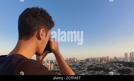 Silhouette di un fotografo che scatta foto sulla parte superiore del edificio al tramonto Foto Stock