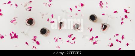Piatto di bicchieri con vino rosso e petali di fiori rosa Foto Stock
