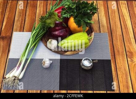 Colorata vita morta di verdure biologiche fresche su piastra di legno su sfondo di legno d'annata, fuoco selettivo, primo piano. Set creativo vegetale. Foto Stock