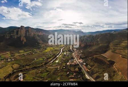 Vista sul drone dei pendii e dei campi di montagna erbosi con infrastrutture in valle Foto Stock