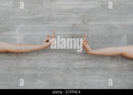 Mani forti abbronzate dell'uomo e della donna del raccolto che gestiscono il dito su sullo sfondo della parete grigia Foto Stock