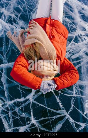 Donna felice in pattini che giacciono su ghiaccio Foto Stock