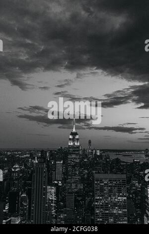 Vista aerea di megalopoli con pareti di vetro illuminate e futuristico facciate di alti grattacieli sullo sfondo in serata Foto Stock