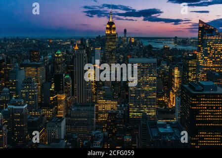Vista aerea di megalopoli con pareti di vetro illuminate e futuristico facciate di alti grattacieli sullo sfondo di un maestoso tramonto Foto Stock