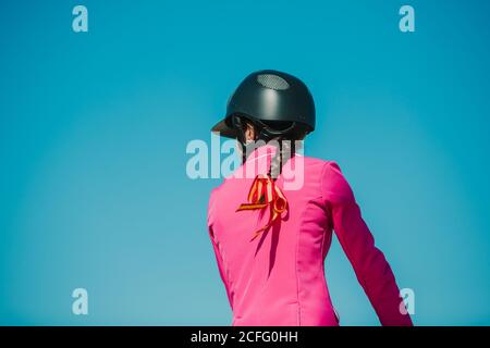 Vista posteriore di anonimo fantino ragazza a cavallo su pista contro un cielo blu in una giornata di sole Foto Stock