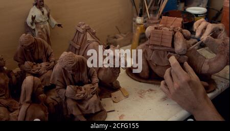 Crop persona lisciatura statuetta di cammello di argilla decorativa su tavola in ceramica Foto Stock