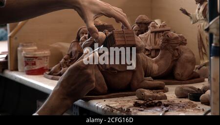 Crop persona lisciatura statuetta di cammello di argilla decorativa su tavola in ceramica Foto Stock