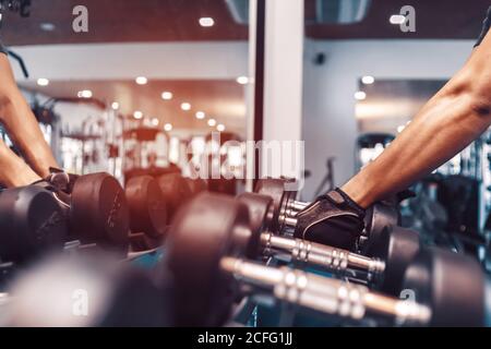 Giovane uomo sportivo che solleva un manubri in palestra. Concetto di fitness, palestra, allenamento e stile lifte. Foto Stock