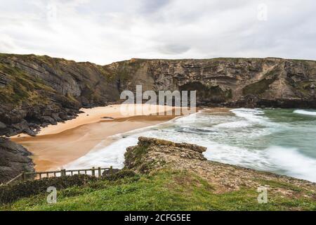 Antuerta spiaggia con le onde in Cantabria, Spagna in una giornata nuvolosa Foto Stock