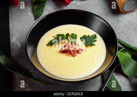 ciotola di gustosa zuppa di crema di formaggio con pancetta su un sfondo grigio Foto Stock