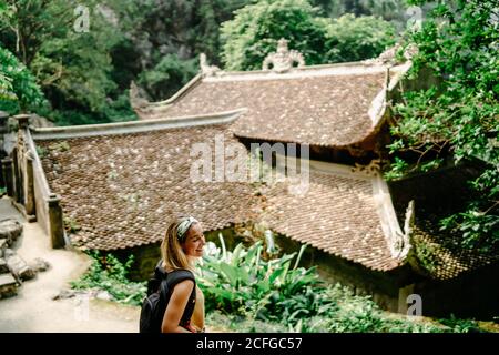 Vista dall'alto del viaggiatore felice con zaino passeggiando in un giardino tropicale vicino a un tempio religioso e godendosi maestoso orizzontale Foto Stock