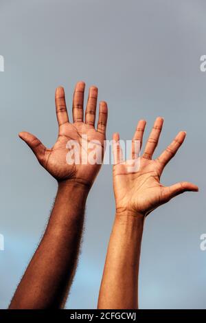 Mano di anonimo uomo nero e Donna contro un cielo blu Foto Stock