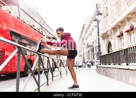 Giovane uomo che allunga le gambe per strada Foto Stock