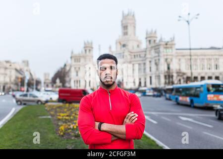 Giovane uomo in piedi per la città indossando abbigliamento sportivo Foto Stock