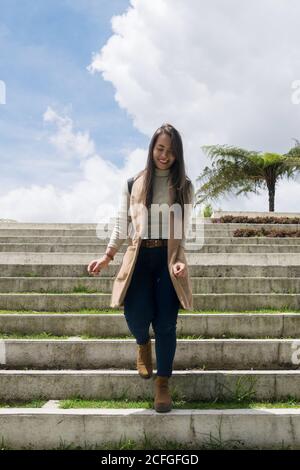 Bella donna in abiti caldi che camminano giù scale di pietra Foto Stock